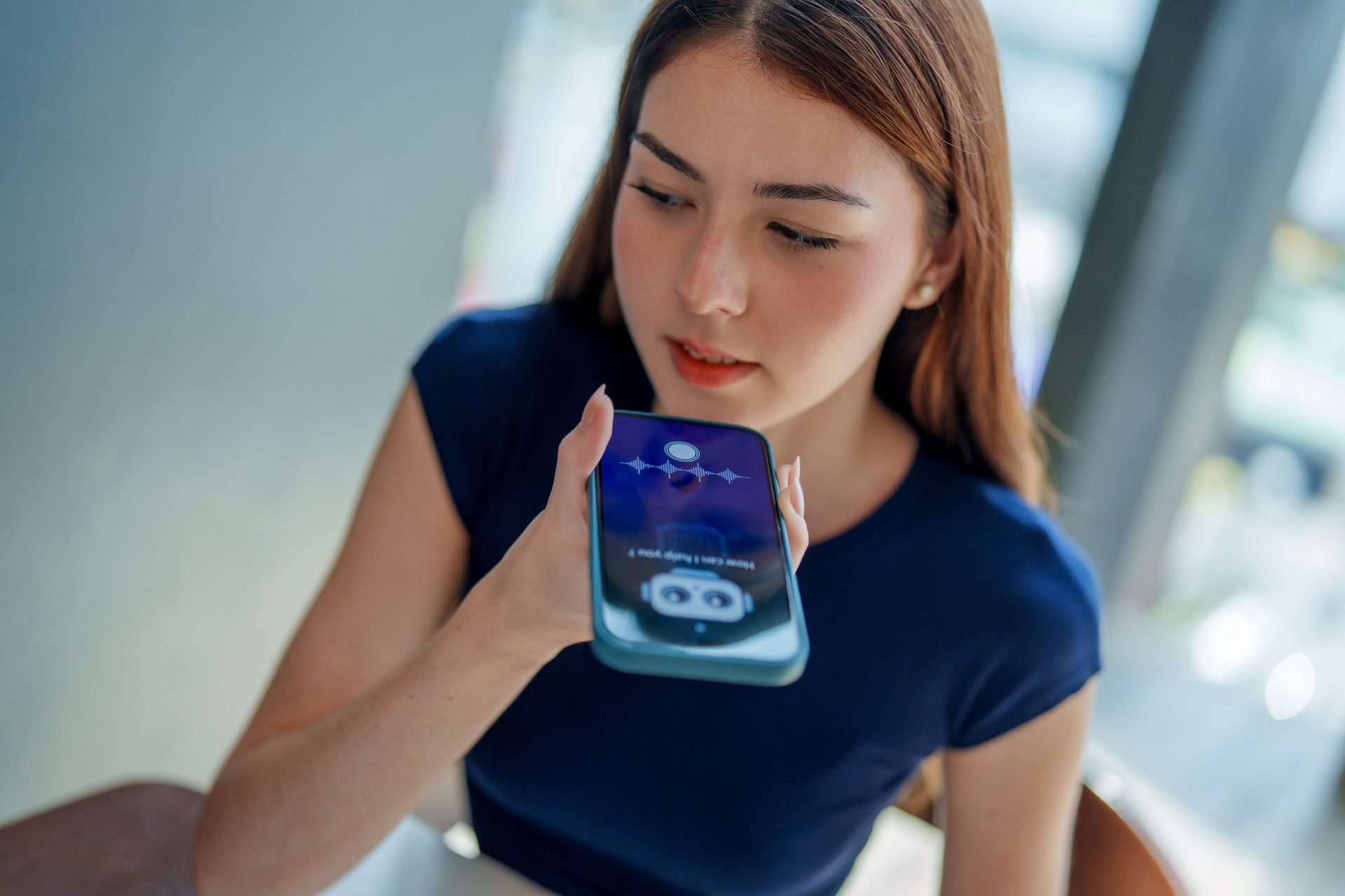 Young woman interacts with smartphone, using voice assistant feature. scene captures modern integration of technology in daily life, showcasing convenience of AI and chatbots in communication